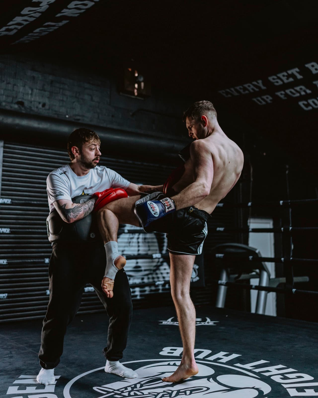 Hayden driving a body kick into the pads on the gym floor at Next Gen Fight Hub