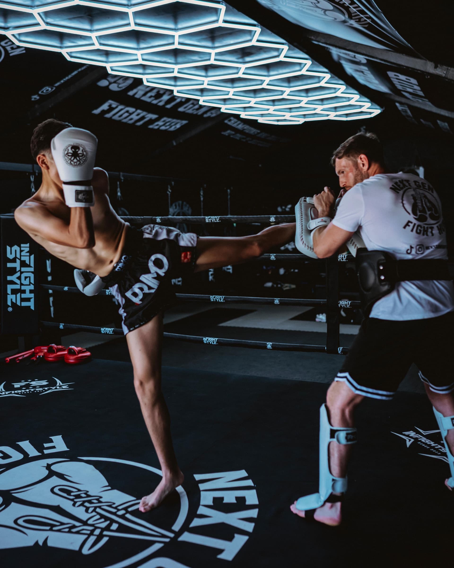 Hayden holding pads for a fighter's head kick in the ring