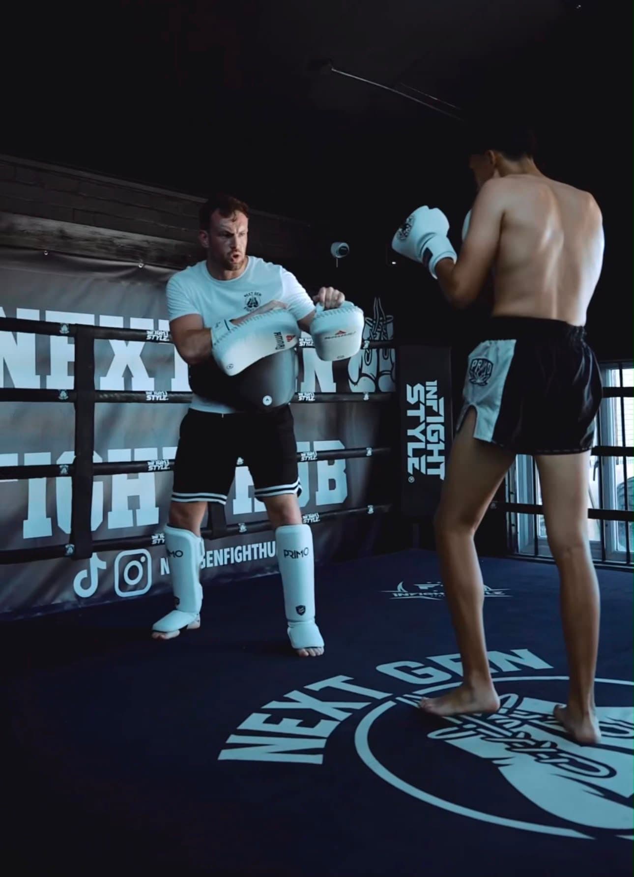 Hayden squared up behind the belly pad while a fighter works combinations in the ring