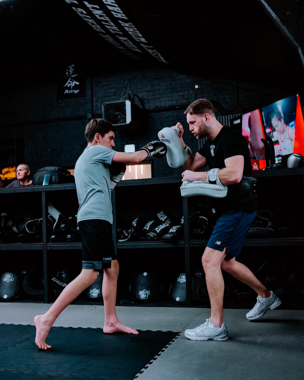 Hayden on the mitts and belly pad with a junior fighter at Next Gen Fight Hub