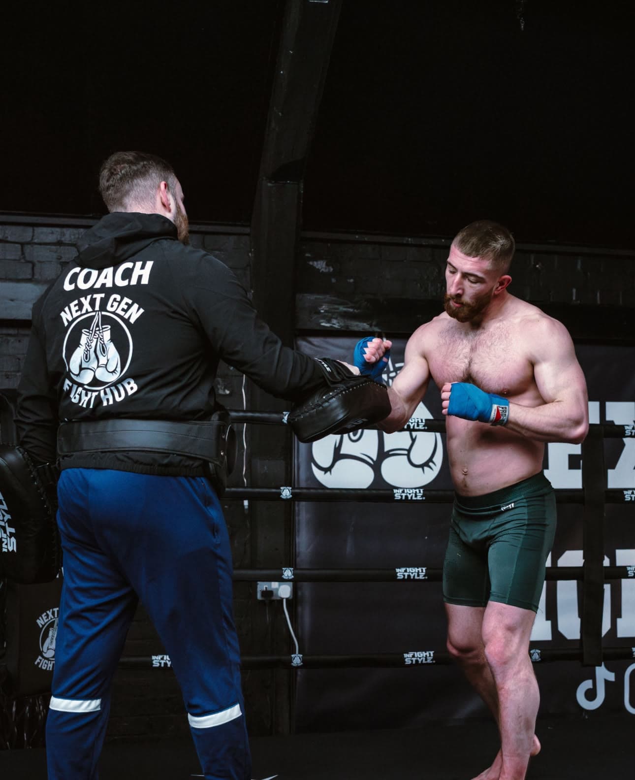 Hayden on the mitts in the ring in his Next Gen Fight Hub coach jacket